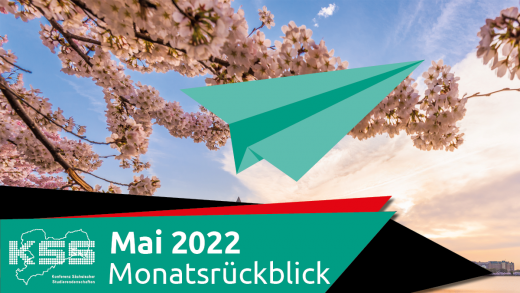 Blühende Bäume im Hintergrund und im Vordergrund ein grüner Papierflieger. Außerdem steht auf dem Bild: Mai 2022 Monatsrückblick