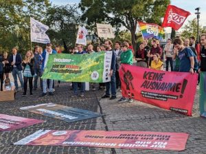 Foto der Demo zum Hochschulgesetz in Dresden. Menschen halten Fahnen ihrer Organisationen und Banner der Hochschulgesetzkampagne Revolution Studium.